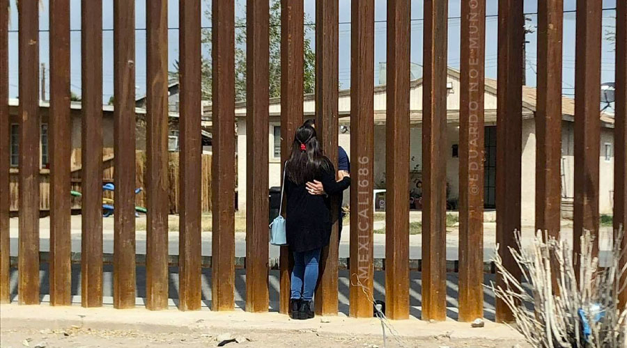 Pareja abrazándose a través del muro entre Estados Unidos y México en Mexicali, BC.